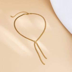 Detail of a golden Y-shaped snake bone necklace with a square buckle and polished finish