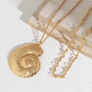 Detailed close-up of golden nautilus shell pendant with textured metallic finish