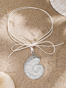 Macro detail of a silver shell pendant with natural nautical textures on white cord