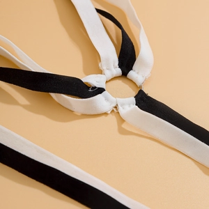 Detail of black and white elastic leg chain straps connected by a silver metal ring