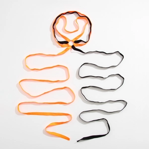 Detail of cross-strapped leg chain with orange and black elastic bands and metal ring