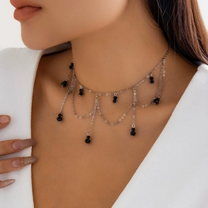 Λεπτομέρεια από ασημί κολιέ choker με μαύρες χάντρες και γοτθικά κρόσσια φούντες
