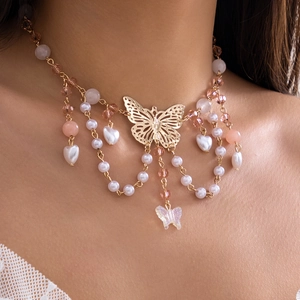 Detail einer goldenen Schmetterling-Perlenkette mit rosa Perlen und Herzanhänger