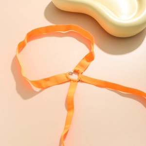 Orangefarbene elastische Beinkette mit silberner Herzschnalle auf warmem Grund