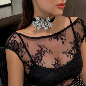 Close-up of black choker necklace with dual sparkling floral rhinestone motifs on model