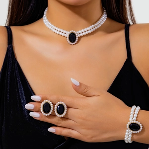 Dettaglio di un set di gioielli con perle vintage e pietra nera su collo e polso