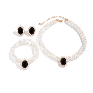 Dettaglio del set di collane e bracciali di perle doppie con pendenti neri e finiture oro