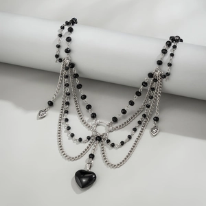 Detail einer mehrlagigen schwarzen Perlen- und Silberketten-Choker mit großem Herzanhänger