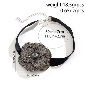 Detail view of a black choker featuring a sparkling rhinestone flower with crystal center