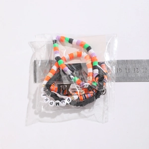 Dettaglio macro del bracciale di perle colorate con lettere PUMPKIN nella confezione