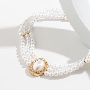 Dettaglio della collana di perle a tre strati con ciondolo dorato e strass lucidi