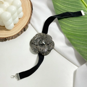 Elegant black suede choker with a large rhinestone camellia flower pendant on white silk