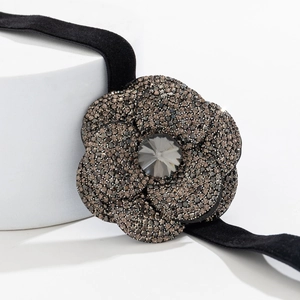 Detail shot of a black velvet choker featuring a crystal-encrusted flower with a grey center