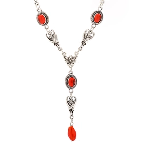 Macro view of gothic bat skull carving and red teardrop pendant on silver necklace