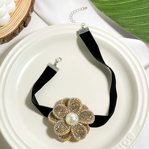Detailed macro view of black velvet choker with rhinestone flower and pearl center