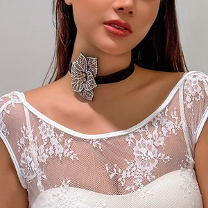 Close-up of black choker with a sparkling rhinestone flower detail on lace clothing