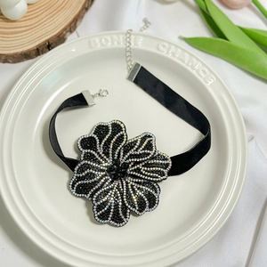 Detail of a black velvet choker featuring a large floral pendant with sparkling rhinestones