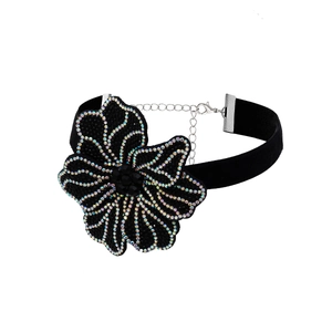 Detail of black velvet choker with a large rhinestone floral pendant and adjustable clasp