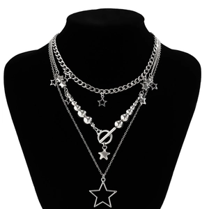 Close-up of layered silver punk necklace with stars, Cuban chain and OT buckle details