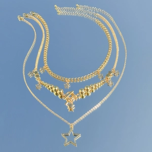 Detail of layered gold star pendant necklace set with T-bar clasp on mirror base