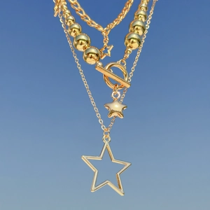 Detail of layered gold star pendant necklaces with ball chain and OT toggle clasp