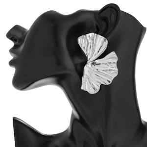 Dettaglio macro di orecchini a foglia di ginkgo argento su busto di manichino nero