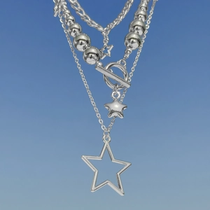 Macro view of multi-layer silver necklaces with star charms and polished metallic beads