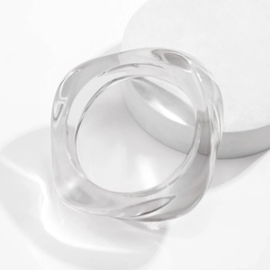 Close-up of translucent acrylic chunky bracelet with irregular wavy design on a stone stand