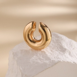 Detailed view of thick C-shaped gold ear cuff with polished mirror finish on stone