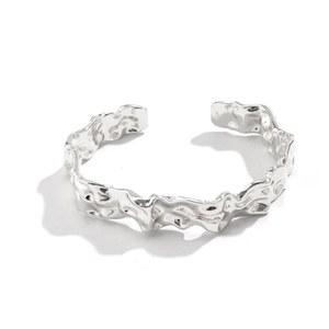 Detailopname van de onregelmatige lavatextuur op de zilveren open armband voor dames