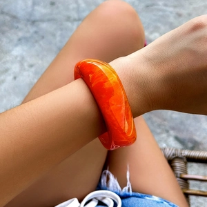 Macro detail of amber resin bracelet showing marble-like textures and polished surface