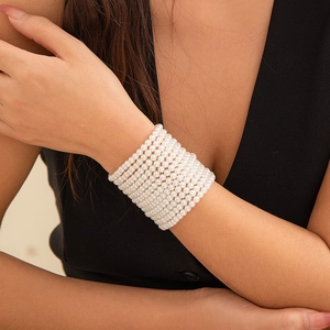 Detalle de una pulsera multicapa de perlas sintéticas con elegante acabado crema