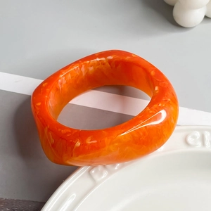 Detail view of bold orange irregular resin bangle with artistic marbled texture