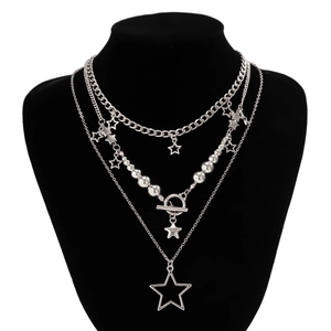Close-up of layered silver star pendant necklaces on a black velvet display