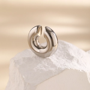 Macro view of polished silver C-shaped ear cuff on stone base showing sleek metallic finish