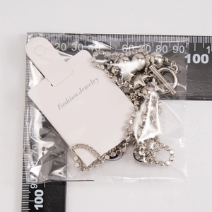 Silver star pendant necklace with beaded chain shown against a scale for size measurement