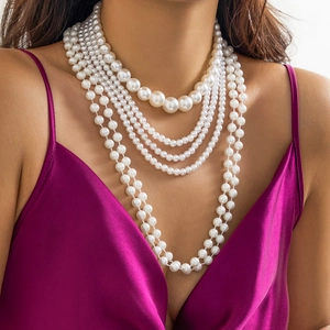 Detalle de collar de perlas blancas de varias capas con un vestido de satén morado