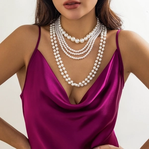 Detalle de collar de perlas artificiales multicapa en una modelo con vestido de seda