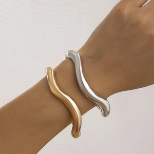Detailopname van sculpturale goud en zilver lava armbanden om de pols van model