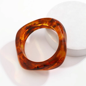 Detail of amber tortoiseshell resin bangle with irregular square geometry and translucent texture