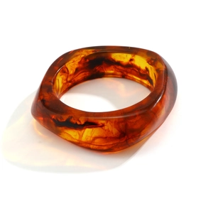 Detailed macro view of an amber resin geometric wide bangle with artistic inner swirl textures