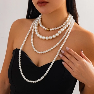 Primer plano de collar de perlas blancas de cuatro capas con detalle de cuenta dorada
