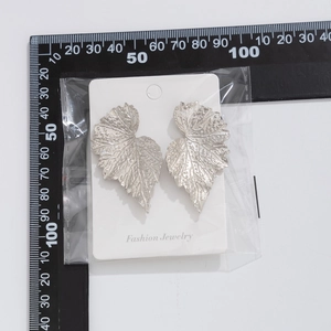 Dettaglio di grandi orecchini a foglia d'argento con trama su carta per gioielli