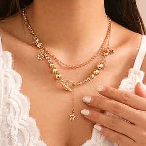 Detail of double-layer gold star pendant necklace with bead chain and T-bar toggle clasp