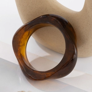 Macro view of wide translucent amber acrylic resin bangle with irregular wavy edges