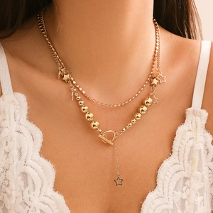 Close-up of golden layered bead necklace with star pendant and toggle clasp on model