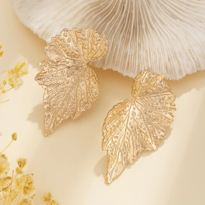 Dettaglio macro di orecchini a foglia di ginkgo dorati con venature in rilievo