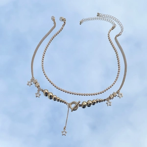 Close-up of double layer gold star pendant necklace with toggle clasp on a mirror surface