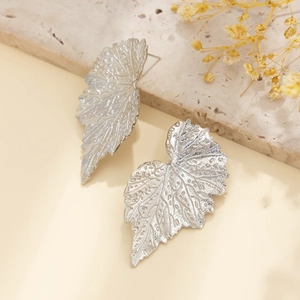 Dettaglio macro di orecchini a foglia di ginkgo argento con trame di venature fogliari