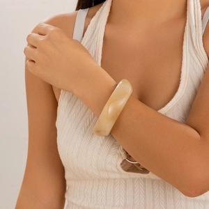 Detail of cream marbled wide acrylic resin cuff bracelet worn on a woman's wrist